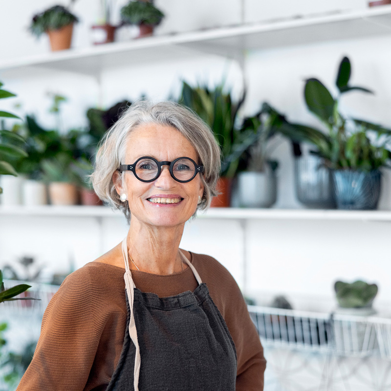 Female horticulturilist smiling whilst surrounded by plants