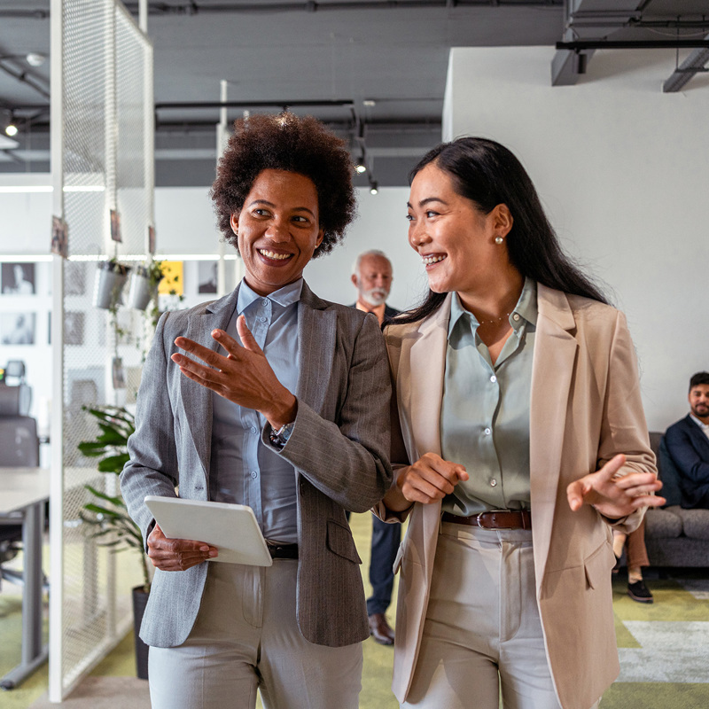 Two young female employees walking through office